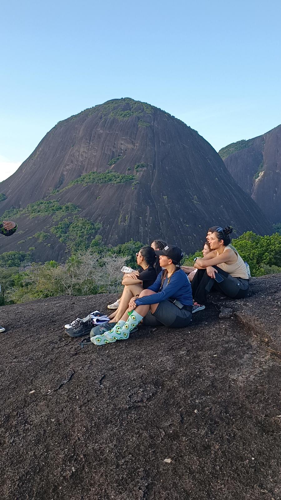 Grupo sentado en la laja viendo el atardecer sobre el cerro