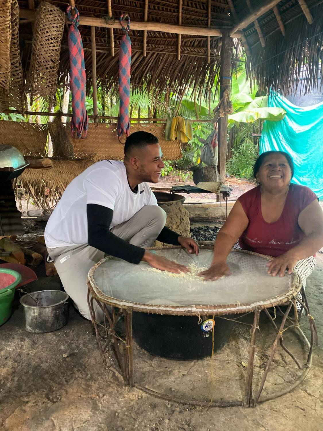 Viajero y mayora de la comunidad cerniendo la yuca brava entre risas