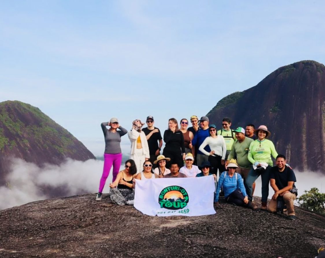 Grupo de viajeros sobre las nubes en la cima, con la bandera de Bonturi-ot tour