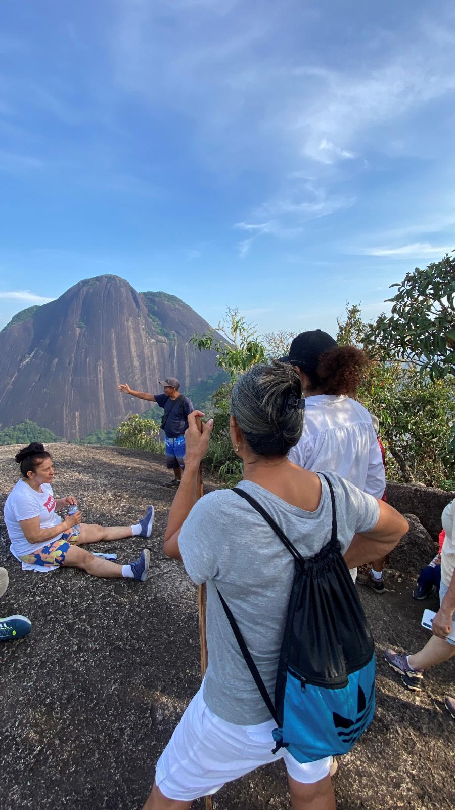 Guía nativo explicando el territorio al grupo desde la cima
