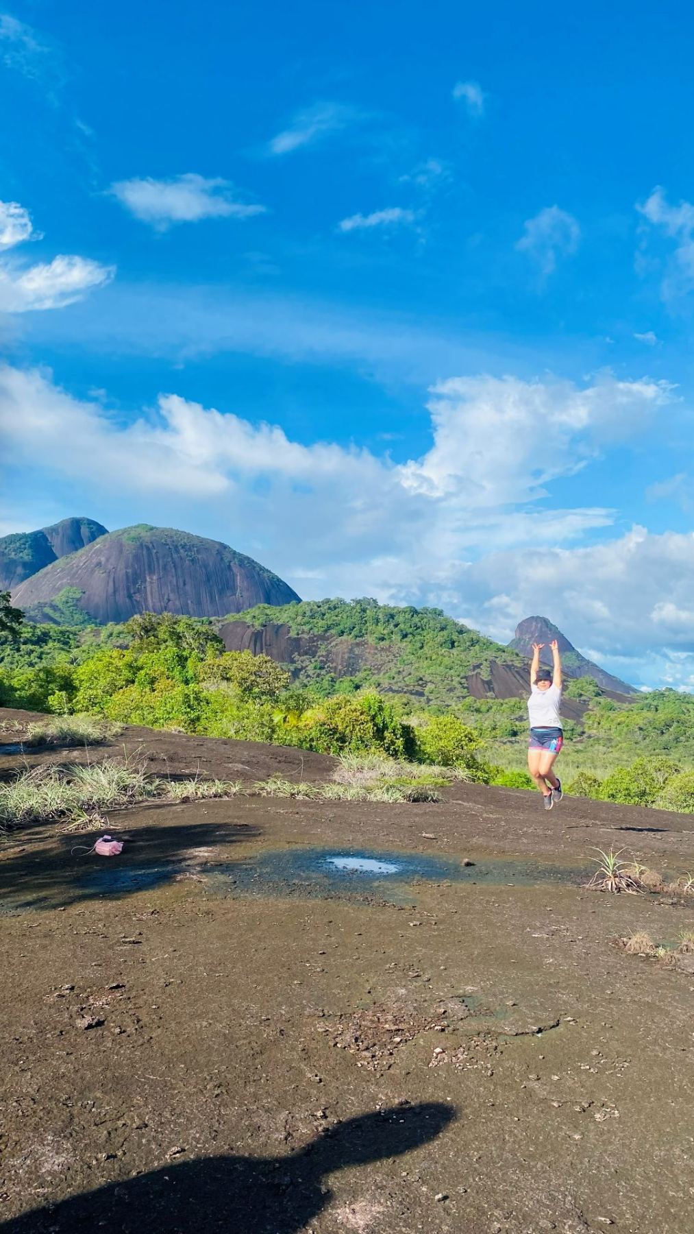 Viajera saltando sobre la laja con los cerros de fondo